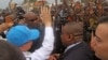 Photo taken April 5, 2014, 2014 shows U.N. Secretary-General Ban Ki-moon, in a cap, waving at people kept back by a wire fence, as he walks surrounded by U.N. security personnel in a secured location in Bangui, Central African Republic.