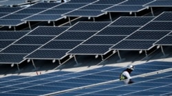 FILE - A worker installs solar panels on a roof at Van Nuys Airport in Los Angeles, California, Aug. 8, 2019.