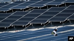 FILE - A worker installs solar panels on a roof at Van Nuys Airport in Los Angeles, California, Aug. 8, 2019.