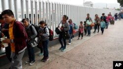 FILE - People line up to cross into the United States to begin the process of applying for asylum near the San Ysidro port of entry in Tijuana, Mexico, July 26, 2018. 