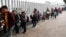 FILE - People line up to cross into the United States to begin the process of applying for asylum near the San Ysidro port of entry in Tijuana, Mexico, July 26, 2018. 