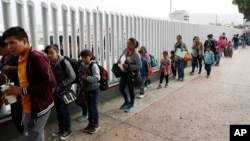 FILE - People line up to cross into the United States to begin the process of applying for asylum near the San Ysidro port of entry in Tijuana, Mexico, July 26, 2018. 