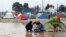 在希腊与马其顿边界的一个临时搭建的难民营里，移民试图在雨中做饭。（2016年3月9日）