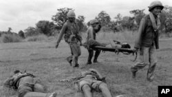 Three Khmer Republican soldiers carry a wounded comrade past two dead soldiers north of Phnom Penh, in 1975. The Khmer communists kept Republican troops busy around the capital while the communists fought for total control of the Mekong River in the south