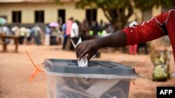 Un électeur dépose son bulletin de vote dans l'urne dans le district de Wakiso, en Ouganda, le 19 février 2016. (Photo AFP)