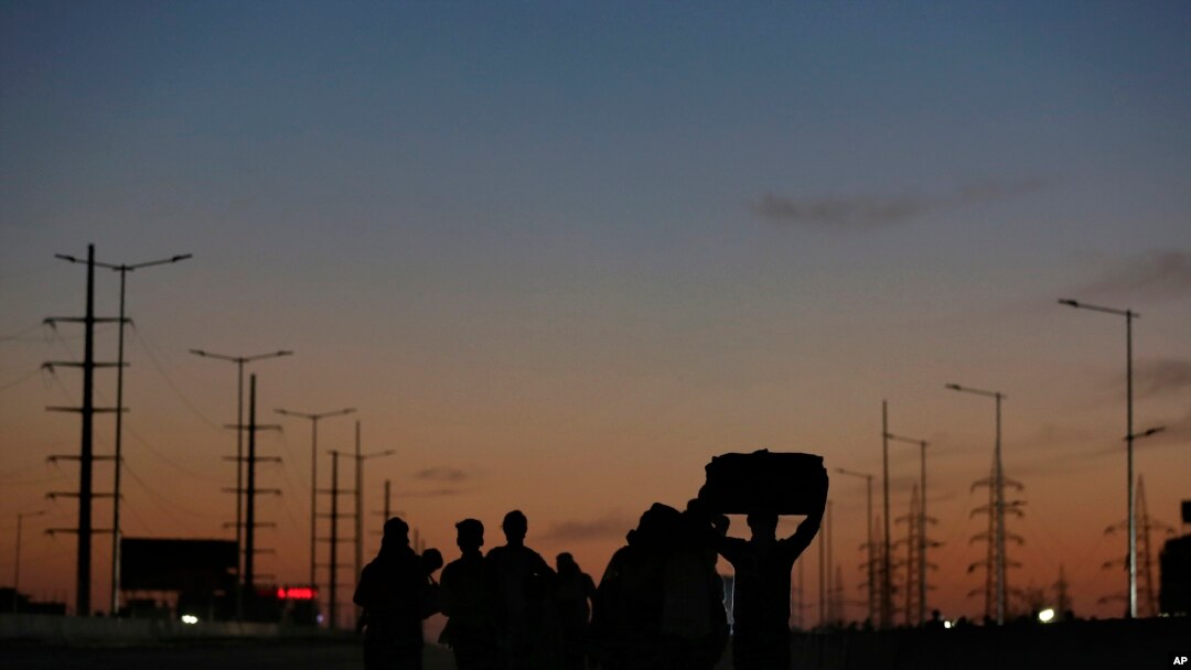 An Indian migrant laborer's family is silhouetted as they make the journey to their village by foot following a lockdown amid concern over spread of coronavirus in New Delhi, India, March 28, 2020.