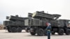 FILE - Russian soldier in ceremonial uniform stand by Pantsir-S SA-22 surface-to-air missile systems during the Victory Day military parade, at the Russian military Hmeimim base in south-east of the Syrian city of Latakia. 