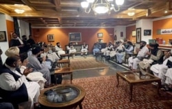 FILE - Former Afghan President Hamid Karzai, accompanied by the old government's main peace envoy, Abdullah Abdullah, sits for talks with members of the Taliban delegation in this undated handout.