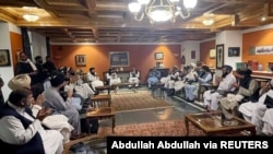 Former Afghan President Hamid Karzai, accompanied by the old government's main peace envoy, Abdullah Abdullah, sits for talks with members of the Taliban delegation in this undated handout, Aug. 19, 2021.