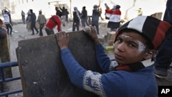 An Egyptian boy takes cover while others throw stones during clashes with the security forces near the interior Ministry in downtown Cairo, Egypt, February 3, 2012.