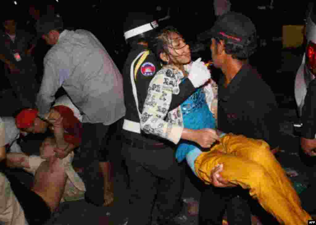 An injured Cambodian is carried by police officers and another visitor after a stampede in Phnom Penh, Cambodia, Monday, Nov. 22, 2010. Thousands of Cambodians celebrating a water festival by the river in the Cambodian capital stampeded Monday night, 