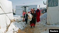 A Syrian refugee family carries 18-day-old triplets, whose mother died during childbirth in a nearby hospital, in a refugee camp near Zahle town in the Bekaa Valley, Lebanon, Jan. 18, 2015.