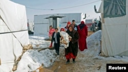 A Syrian refugee family carries 18-day-old triplets, whose mother died during childbirth in a nearby hospital, in a refugee camp near Zahle town in the Bekaa Valley, Lebanon, Jan. 18, 2015.