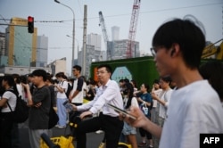 FILE - People wait to cross a road near a construction site in Beijing on July 9, 2024. China said on September 13 it would gradually raise its statutory retirement age, as the country grapples with a looming demographic crisis and an older population. (Photo by Greg Baker / AFP)