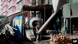 A worker prepares to load cement on a crane at a residential building under construction in in Xiahe, Gansu Province, China, Oct. 17, 2013. 