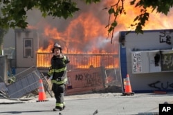 FILE - Construction buildings burn near the King County Juvenile Detention Center in Seattle, July 25, 2020.