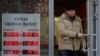 FILE - A man leaves a bank next to an exchange sign showing the currency exchange rates in Moscow, Dec. 20, 2024. 