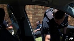 FILE - A man on the ground, suspected of driving a stolen vehicle, is apprehended by private security personal, right, in a suburb east of Johannesburg, South Africa, December 1, 2023.