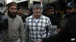 U.S. consulate employee, identified as Raymond Davis, is escorted by police and officials out of court after facing a judge in Lahore, January 28, 2011