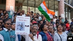 Para pengunjuk rasa di Kolkata, India, Senin, 20 Januari 2025, membawa poster bertuliskan "siapa yang berani kau hakimi, Sanjay bukan satu-satunya penjahat" dan meneriakkan yel-yel menuntut penyelidikan lebih lanjut terkait kasus pembuhunan dokter magang. (Bikas Das/AP)