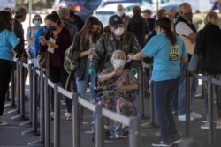 People wait in line to be vaccinated at a super vaccination station set up in an empty department store during the outbreak of the coronavirus in Chula Vista, California, Jan. 21, 2021.
