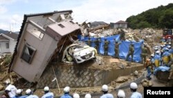 Petugas penyelamat mencari orang-orang yang hilang di sebuah rumah yang ambruk akibat hujan lebat yang melanda kota Kumano, Prefektur Hiroshima, Jepang, 9 Juli 2018. (Kyodo/via Reuters)