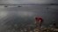 FILE - A man washes himself in the polluted waters of Guanabara Bay in Rio de Janeiro, Brazil, July 30, 2016. 