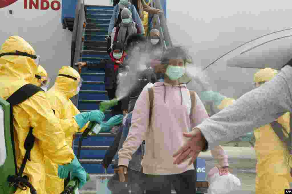 This handout photo released by the Indonesian Embassy shows officials in full protective gear disinfecting Indonesian students as they disembark upon the arrival at Hang Nadim international airport in Batam, following their evacuation from the Chinese city of Wuhan due to the coronavirus outbreak.