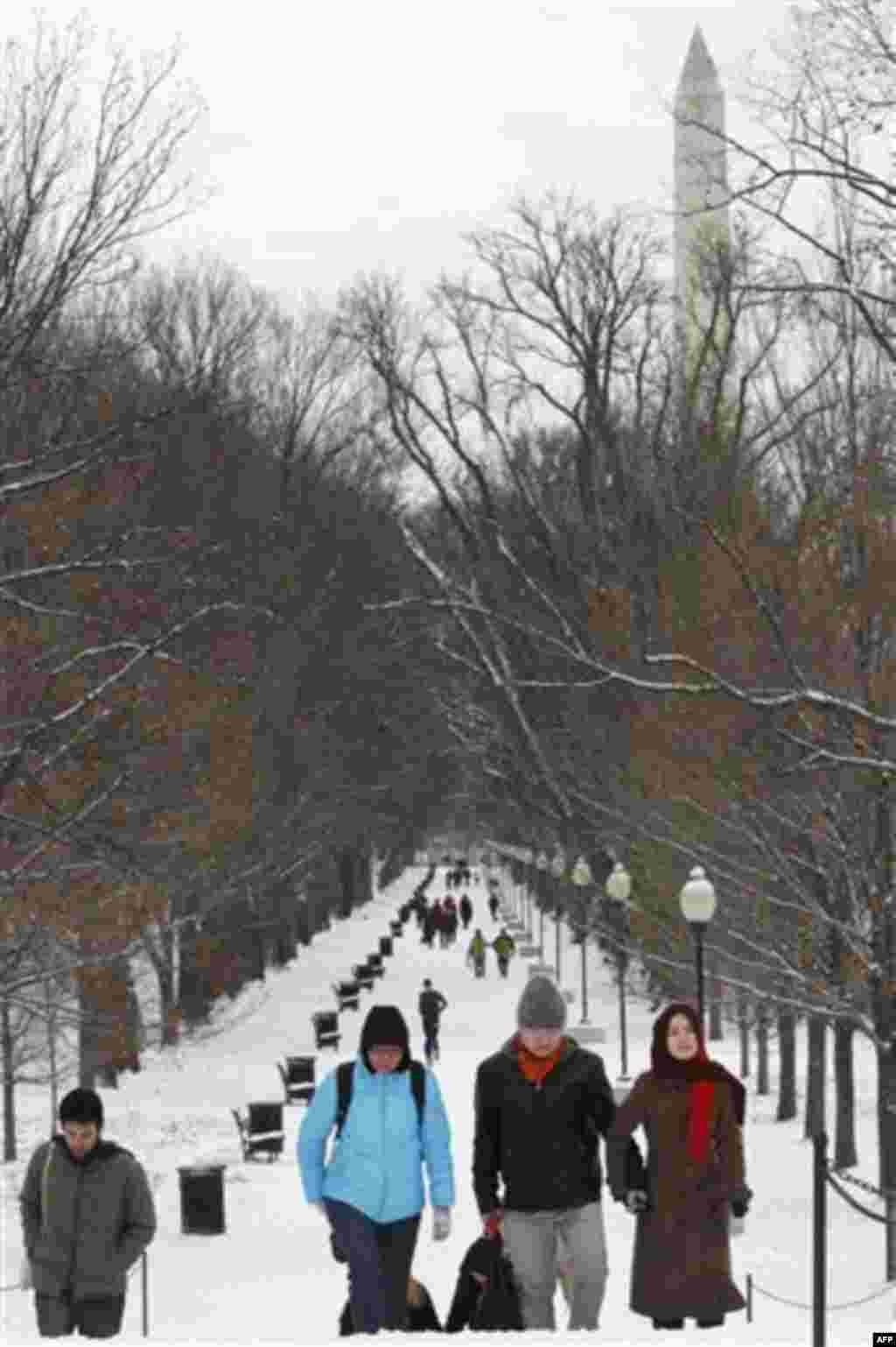 With the Washington Monument in the background, bundled up people walk through the snow on the National Mall in Washington, on Thursday, Dec. 16, 2010. (AP Photo/Jacquelyn Martin)