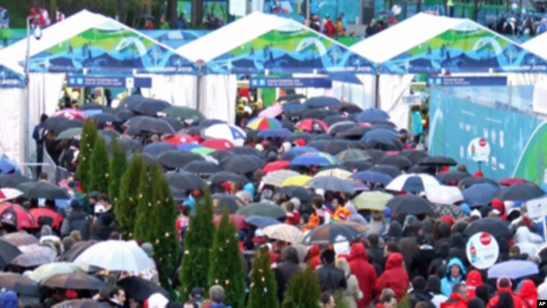 Visitors line up to enter the Winter Games venues on opening day. Umbrellas were plentiful, snow was not