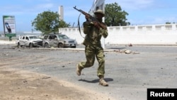 FILE - Somali government soldier runs to take position in front of the Parliament during fighting between them and al-Shabab militia in the capital Mogadishu, May 24, 2014. 