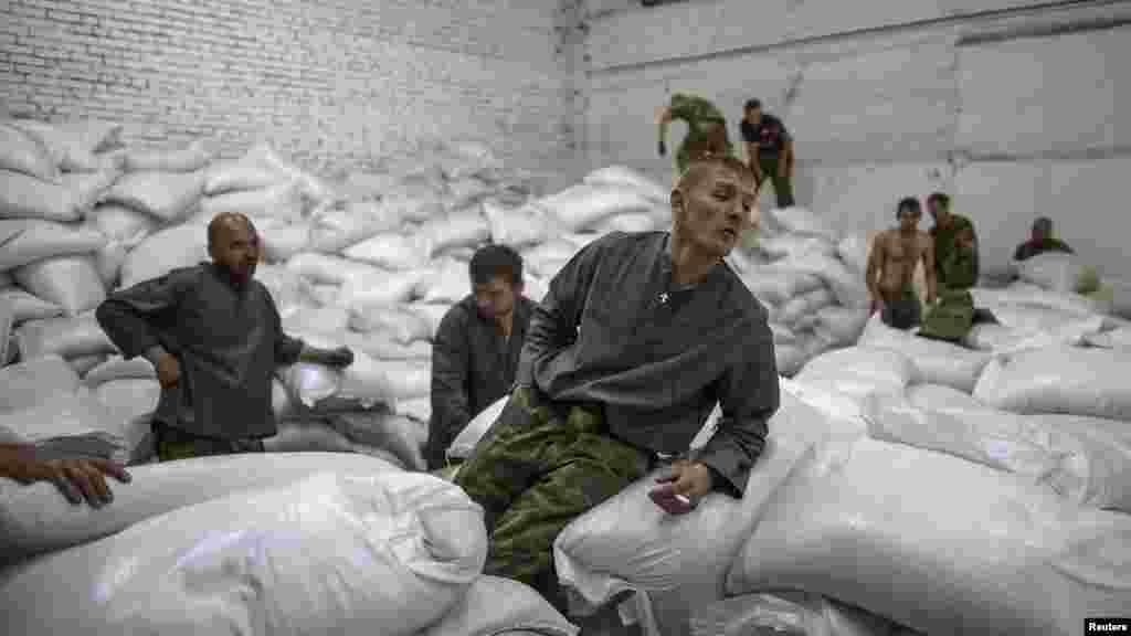 A man sits on sacks which are part of a Russian convoy carrying humanitarian aid in Donetsk, eastern Ukraine, Sept. 20, 2014. 