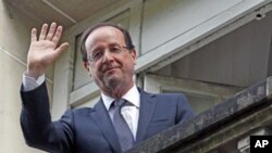 France's newly-elected President Francois Hollande waves from a balcony at his campaign headquarters the day after his election, in Paris, May 7, 2012.