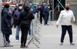 People stand in line as they wait to get tested for COVID-19 at a just-opened testing center in the Harlem section of New York, April 20, 2020.