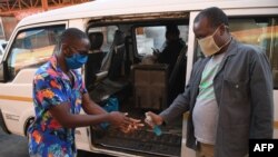 FILE - A man receives hand sanitizer as a preventive measure against the spread of the COVID-19 coronavirus before boarding a taxi in Gaborone, May 21, 2020.
