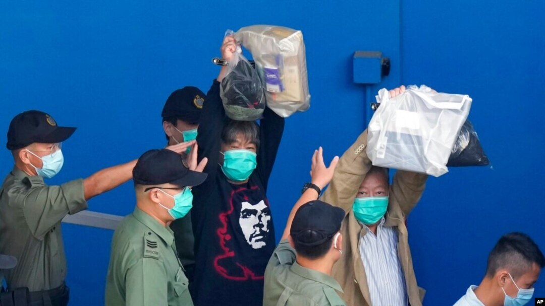 Aktivis pro-demokrasi Leung Kwok-hung, yang dikenal sebagai "Rambut Panjang," kiri, dan Lee Cheuk-Yan mengangkat tangan saat mereka dikawal oleh petugas Layanan Pemasyarakatan ke sebuah van penjara untuk pengadilan di Hong Kong, 28 Mei 2021. (Foto: AP)