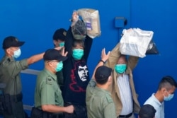 Pro-democracy activists Leung Kwok-hung, known as "Long Hair," left, and Lee Cheuk-Yan raise their hands as they are escorted by Correctional Services officers to a prison van for a court in Hong Kong, May 28, 2021.