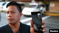 The gunman who has hostaged at least a dozen people shows a grenade on a video call with a policeman, witnessed by members of the media outside a mall in San Juan City, Metro Manila, Philippines, March 2, 2020.