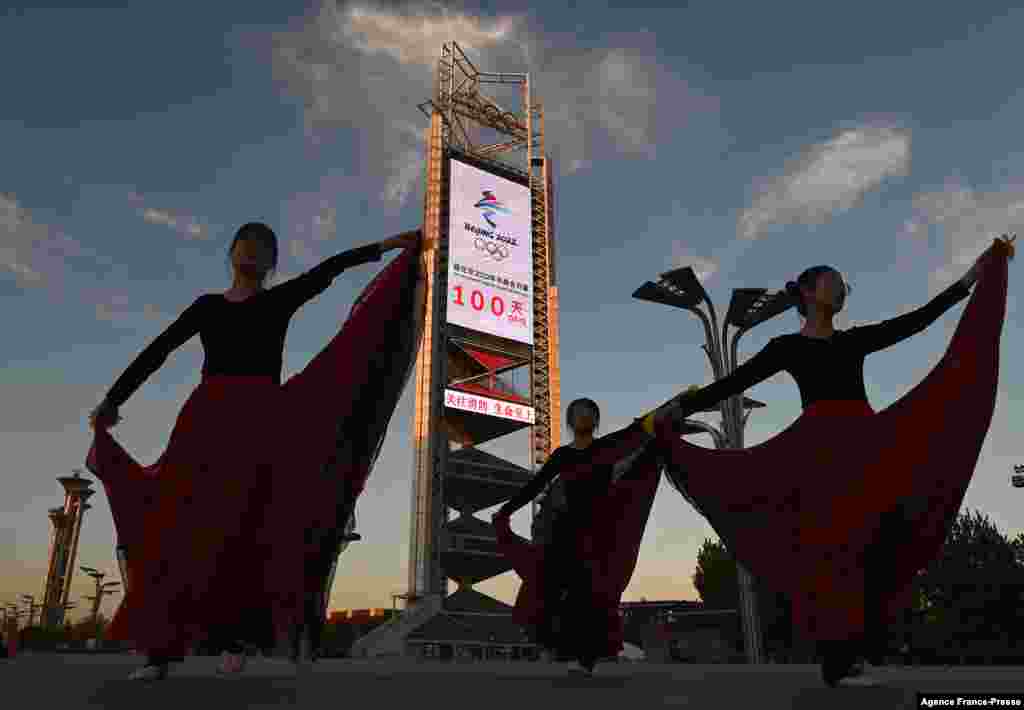 Dancers perform in front of the countdown clock showing 100 days until the opening of the 2022 Beijing Winter Olympics, at the Olympic Park in Beijing, China.
