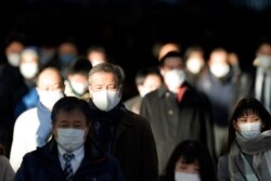 A station passageway is crowded with commuters wearing face masks during rush hour, Jan. 8, 2021, in Tokyo. Prime Minister Yoshihide Suga declared a state of emergency Thursday for Tokyo and three other prefectures to ramp up coronavirus defenses.