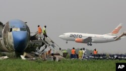 A passenger plane lands as workers dismantle an abandoned aircraft at Murtala Muhammed International Airport in Lagos, Nigeria, January 31, 2013. Nigerian aviation officials have begun trying to dismantle and remove the hulks of abandoned airplanes from 