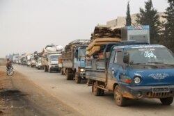 FILE - Trucks carry belongings of people fleeing from Maaret al-Numan, in northern Idlib, Syria, Dec. 24, 2019.
