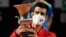 Novak Djokovic dari Serbia merayakan dengan trofi setelah memenangkan final melawan Diego Schwartzman dari Argentina, September 2020. (Foto: Pool via REUTERS/Riccardo Antimiani)