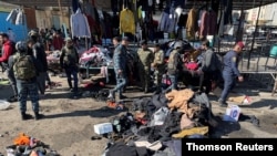 Members of Iraqi security forces inspect the site of a twin suicide attack at a central flee market in Baghdad, Iraq, Jan. 21, 2021. 