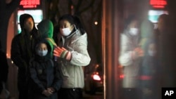 Commuters wearing protection masks, wait for buses at a bus station on a heavy polluted day in Beijing, China, Jan. 2, 2017.