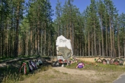 FILE - A giant stone marking the site, known as Sandramokh engraved with the words "People Don't Kill Each Other" at a mass grave where thousands of victims of Stalin's Great Terror were executed, outside Medvezhyegorsk, Russia, Aug. 9, 2006.