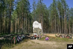 FILE - A giant stone marking the site, known as Sandramokh engraved with the words "People Don't Kill Each Other" at a mass grave where thousands of victims of Stalin's Great Terror were executed, outside Medvezhyegorsk, Russia, Aug. 9, 2006.