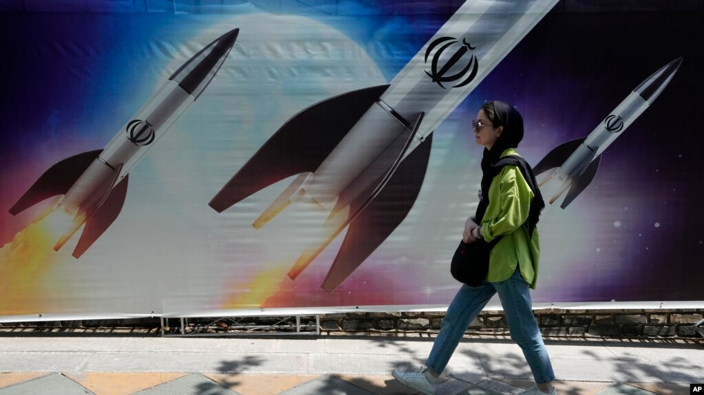 2024 年4 月19日，伊朗德黑兰北部，一名妇女走过显示导弹正在发射的宣传画前。