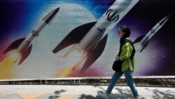 2024 年4 月19日，伊朗德黑蘭北部，一名婦女走過顯示飛彈正在發射的宣傳畫前。
