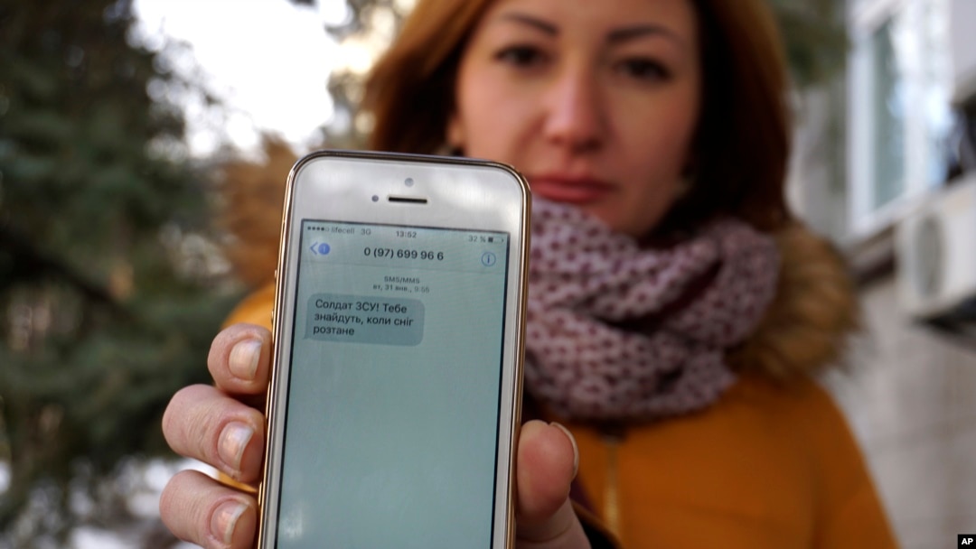FILE - Television journalist Julia Kirienko holds up her smartphone to show a text message reading “Ukrainian soldiers, they’ll find your bodies when the snow melts,” in Kyiv, Ukraine, Feb. 22, 2017.